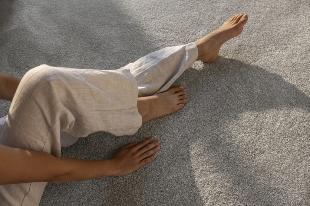 close-up of a woman sitting in a sunny carpeted lounge room.